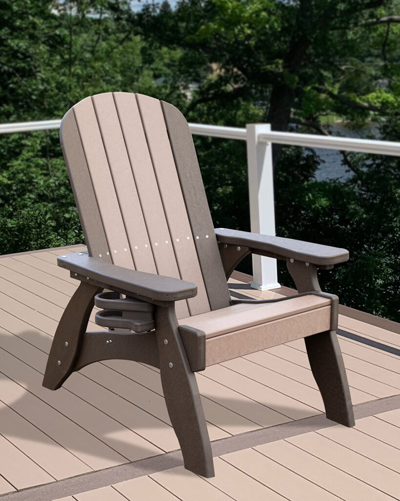 Adirondack chair made of plastic lumber on a wooden deck with white railing, overlooking a lake and surrounded by green trees