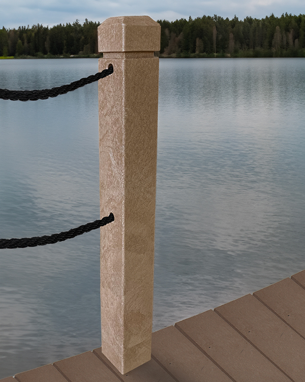 Light brown plastic lumber bollard installed on a lakeside dock, with two black ropes threaded horizontally through it. Calm lake and tree-lined shoreline visible in the background